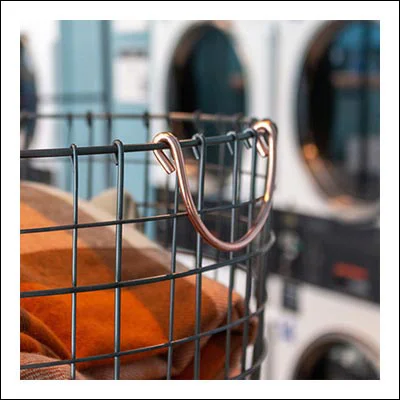 A laundry basket in focus with laundry machines in background